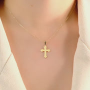 Model wearing the gold cross pendant to illustrate its elegant fit and versatile style.
