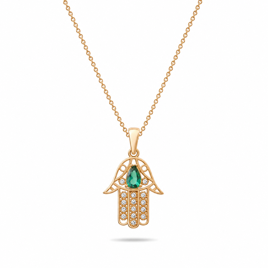 Gold Hamsa hand pendant with a green gemstone on a white background
