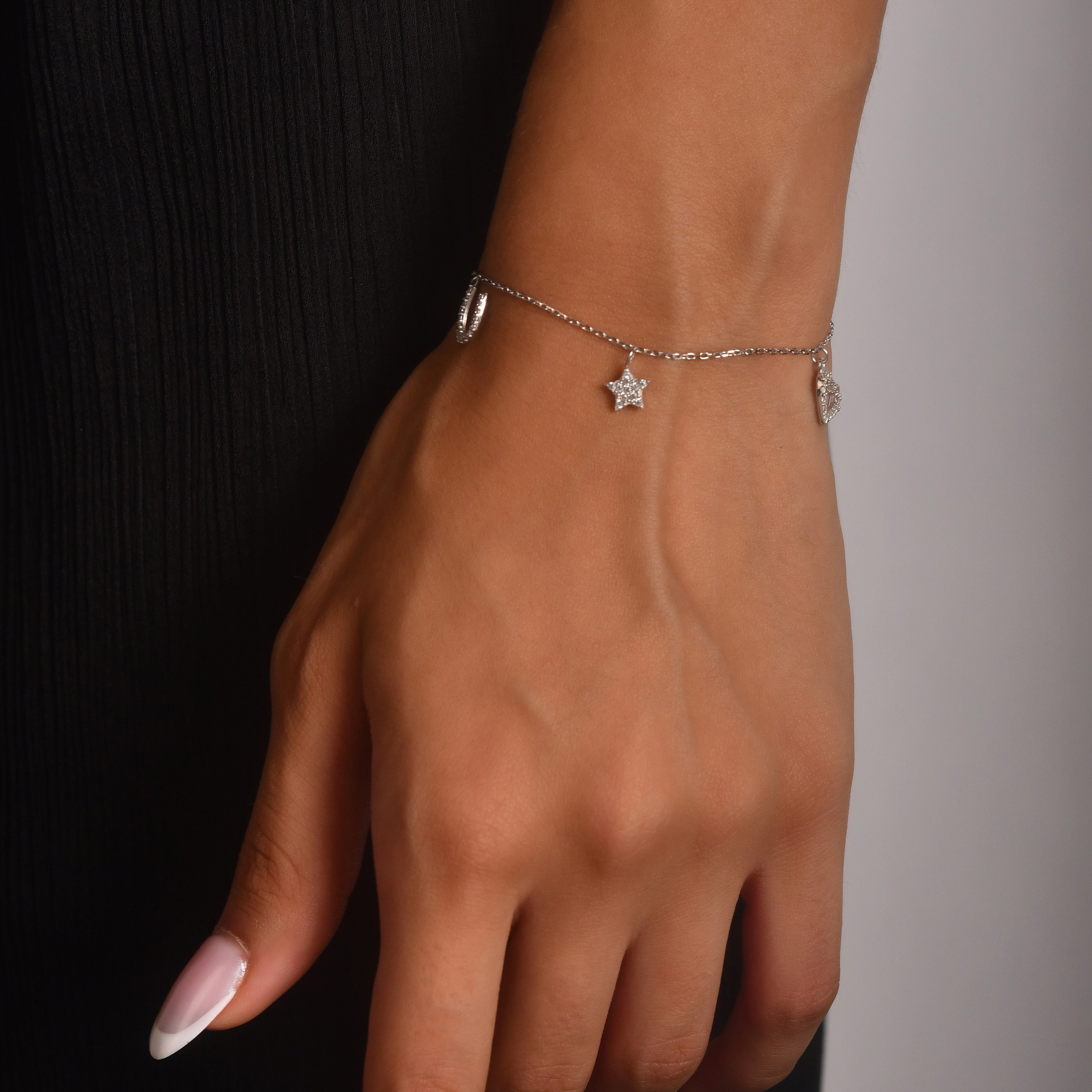 9ct white gold charm bracelet with CZ star and heart charms on model’s wrist