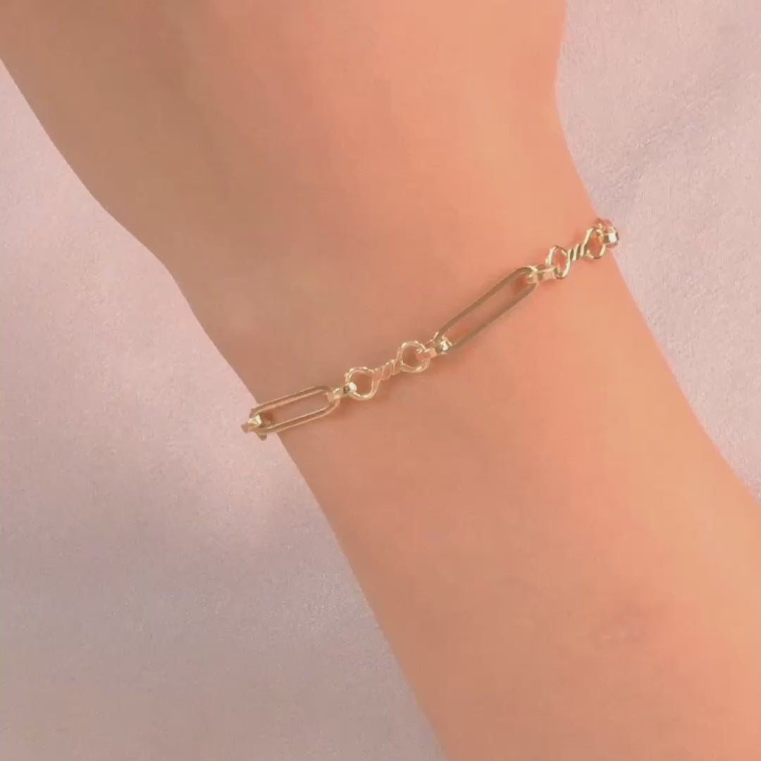 Close-up of the bracelet on a woman's wrist, highlighting the modern paperclip design and polished gold finish.