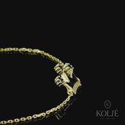 Regal Kolié 9ct yellow gold bracelet showcasing a crown motif set with blue zirconia stones, displayed on black surface. Discover this royal-inspired jewelry piece at www.kolie.co.uk.