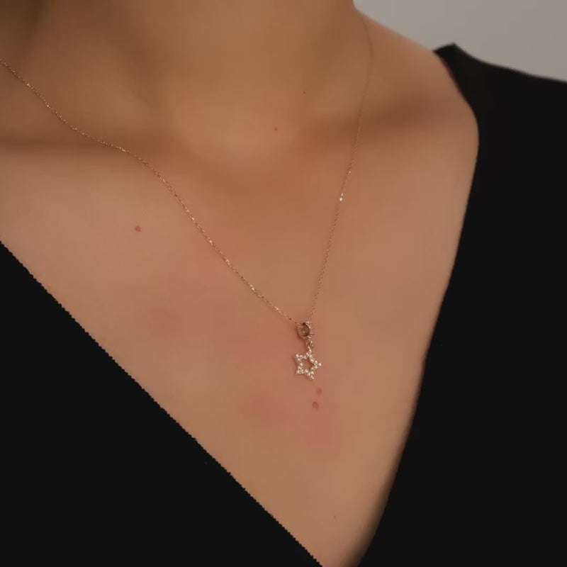 Close-up video of a 14ct gold star necklace with cubic zirconia stones, worn on a woman’s neck.