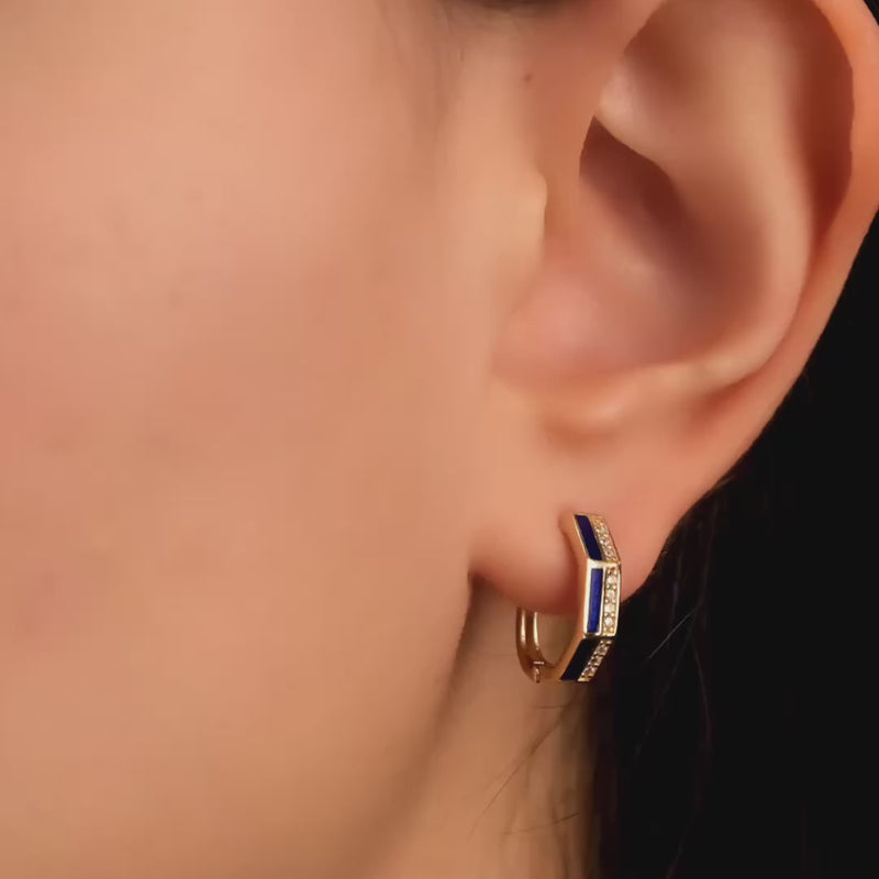 Close-up video of a model wearing solid gold hoop earrings adorned with blue enamel accents and cubic zirconia stones, showcasing a chic and fashionable look.