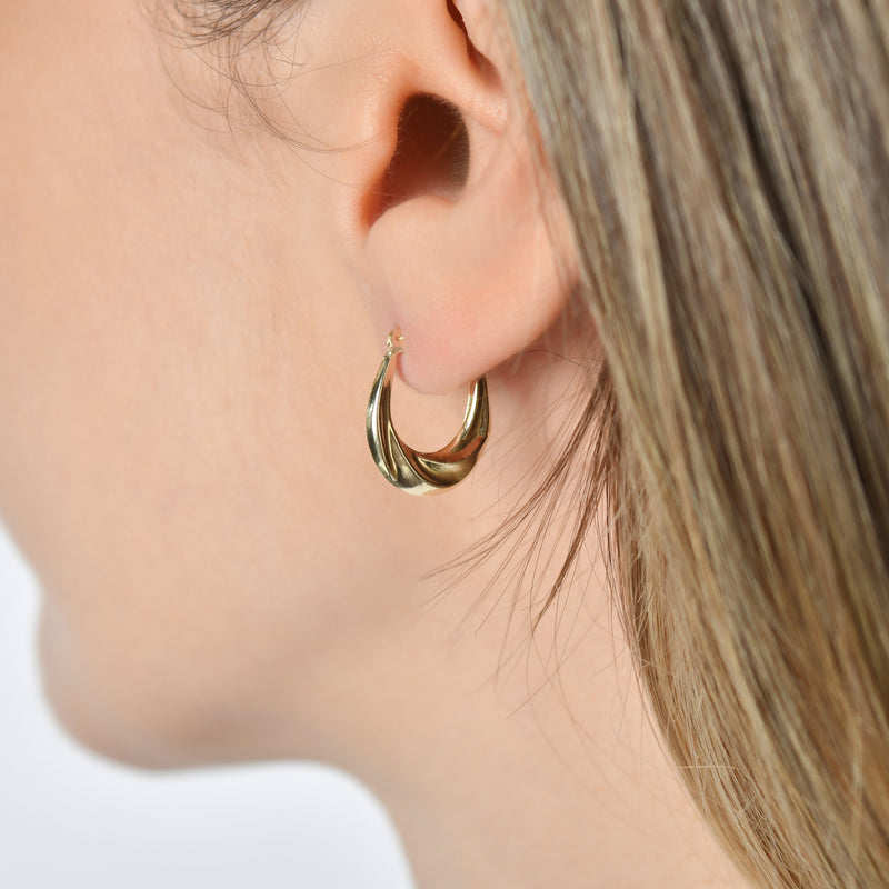 Close-up of Kolié 9ct solid gold swirl hoop earrings, featuring a dynamic, swirling design with a polished finish.