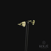 Kolié 9ct yellow gold heart-shaped stud earrings, filled with sparkling zirconia, offering a glimpse of love's radiance against a black background. Find these enchanting earrings at www.kolie.co.uk