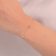 The bracelet displayed on a wrist, highlighting the dainty gold chain and small beads.