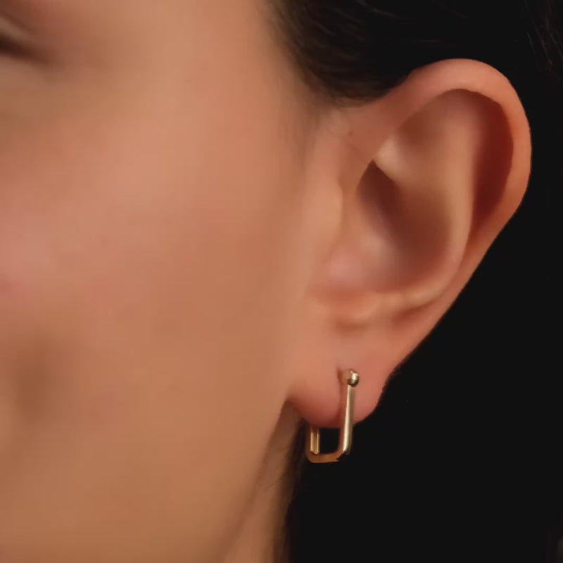 The earrings worn by a woman, demonstrating their elegant and understated fit.