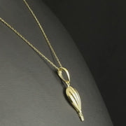 Hot air balloon gold pendant displayed on a balck background, with the chain.