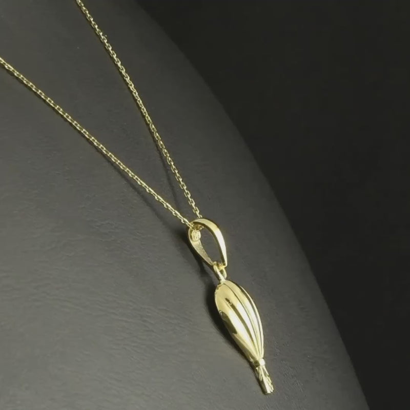 Hot air balloon gold pendant displayed on a balck background, with the chain.