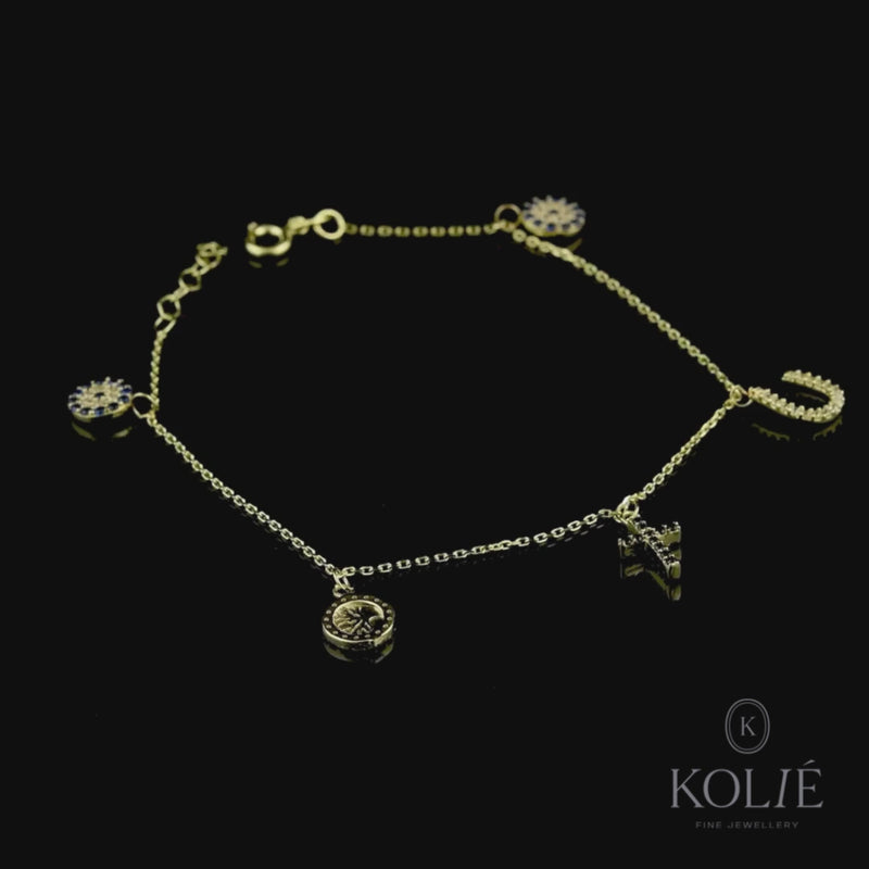 Chic Kolié 9ct yellow gold multi-charm bracelet featuring a mix of horseshoe, cross, tree of life, and evil eye embellished with black and white zirconia stones, arrayed elegantly on a black background. Find this eclectic piece at www.kolie.co.uk.