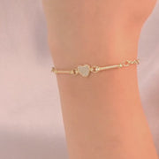 The bracelet on a woman’s wrist, showing the pave heart charm and its delicate gold chain.